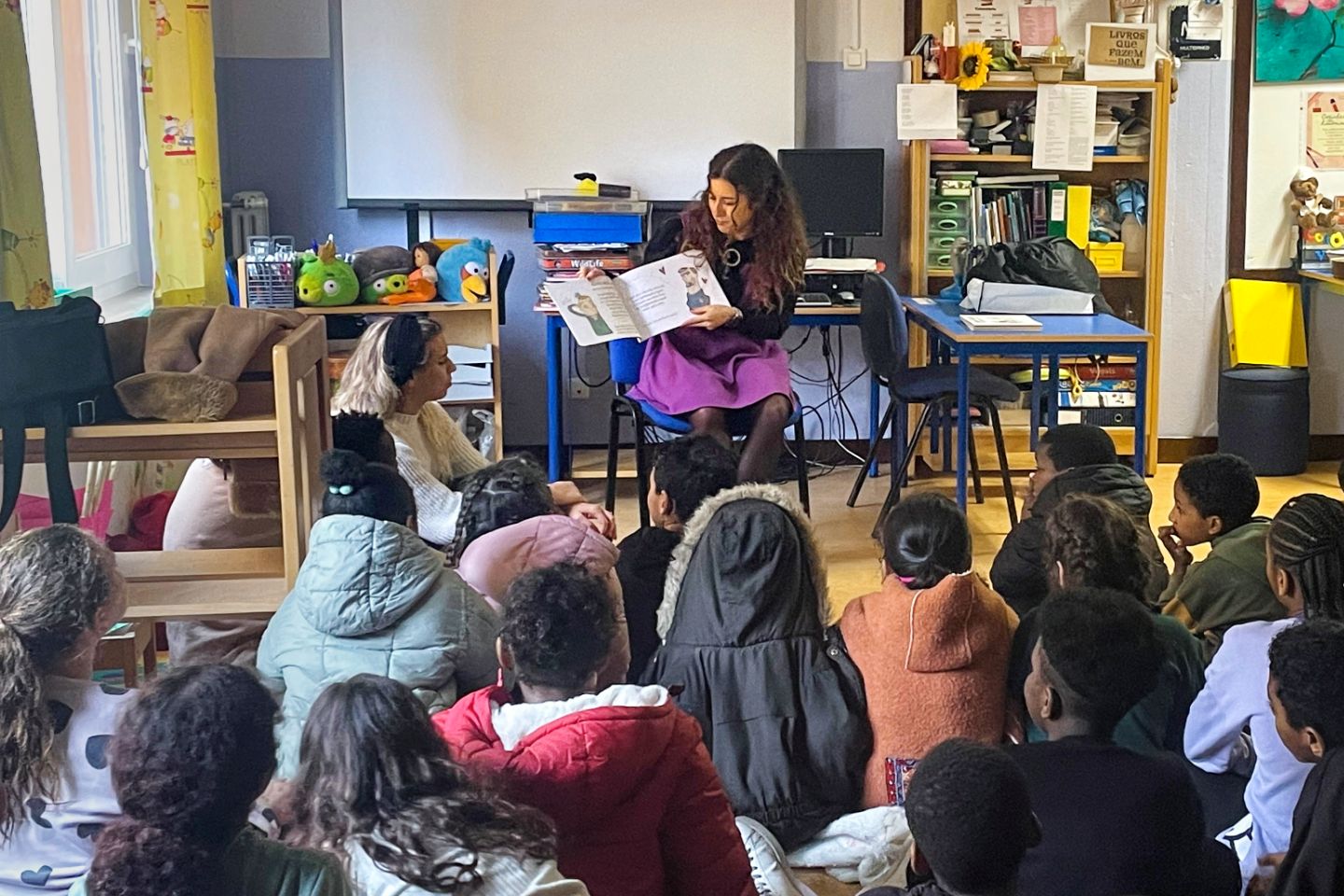 A school class with a person in front presenting a book